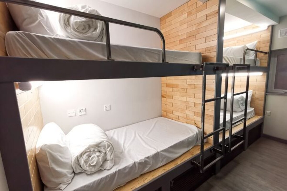 A bunk bed room with a wooden wall, a window, and a power outlet.
