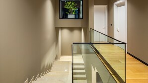 Een modern interieur met een glazen balustrade, een trap en een plant in een pot aan de muur.