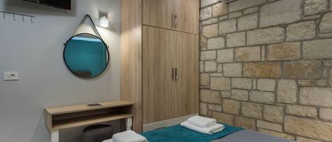 A modern bedroom with a bed, a desk, a mirror, and a TV.