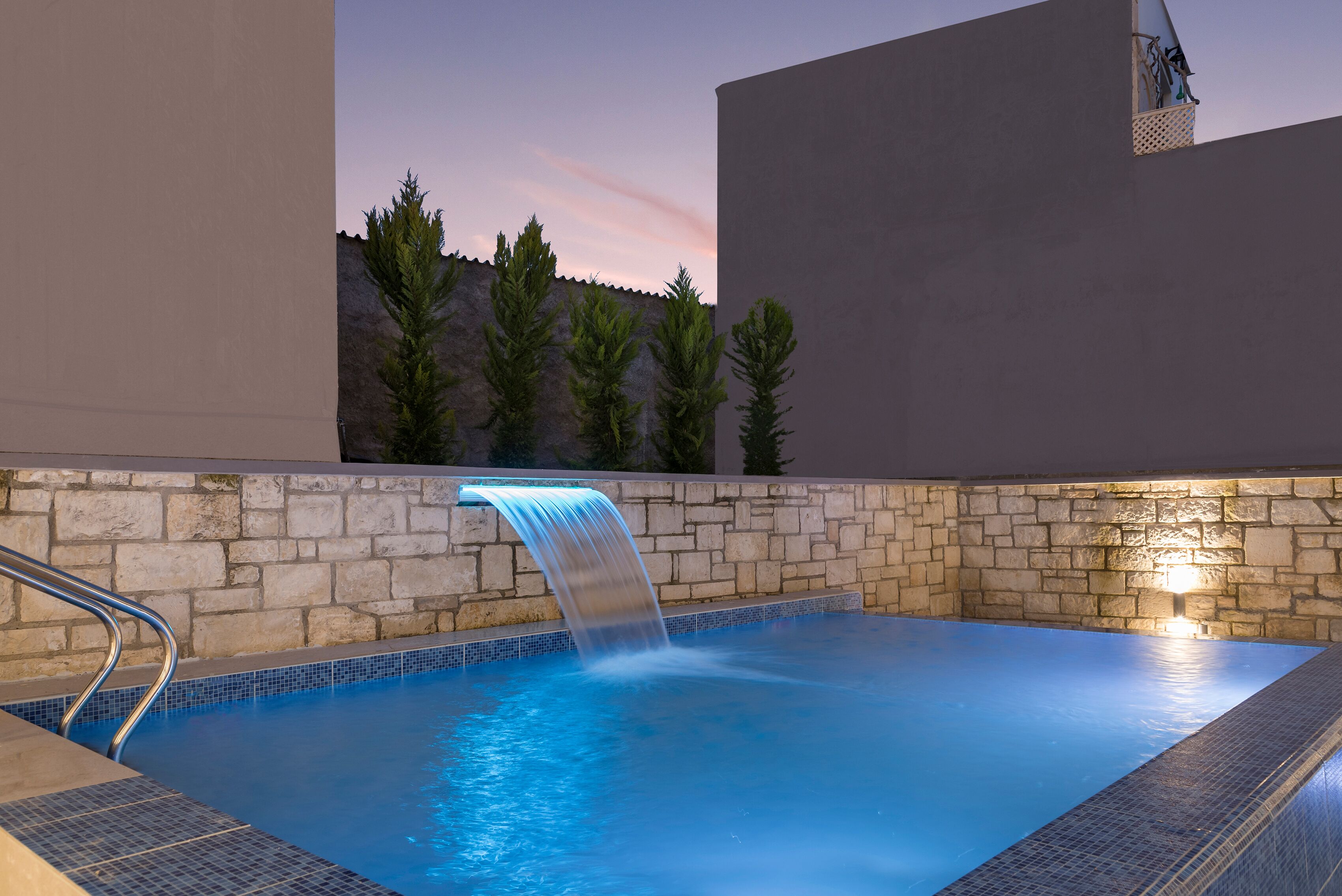 Una piscina al aire libre, sombrillas, sillones reclinables de piscina