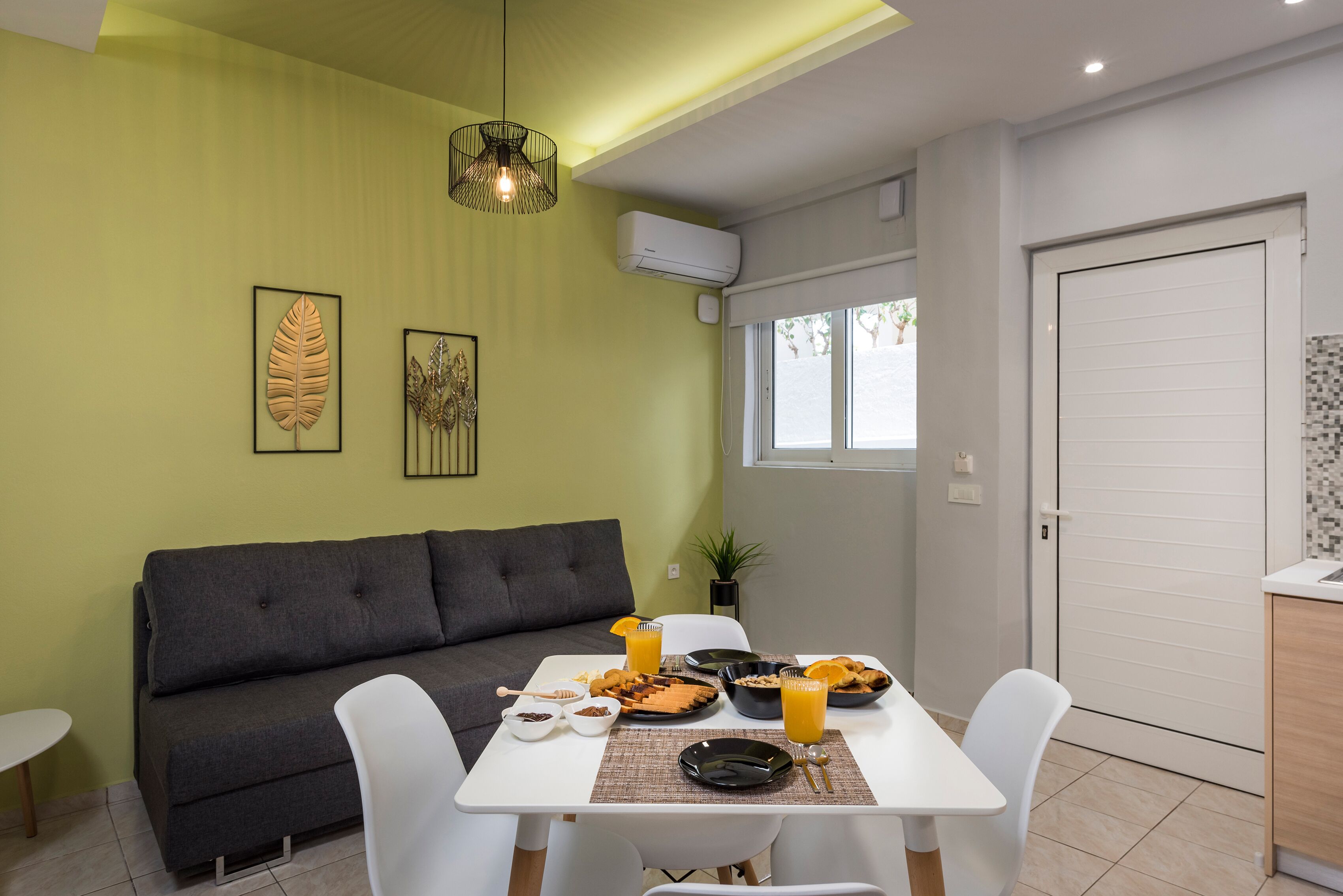 Un coin repas avec une table mise pour le petit-déjeuner, un canapé et une fenêtre donnant sur un beau paysage.