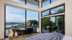 A modern room with large windows, a desk, two fluffy dogs, and a cozy gray blanket. - KAURI HILL ESTATE Luxe Retreat Overlooking Whangaroa Harbour (Northland)