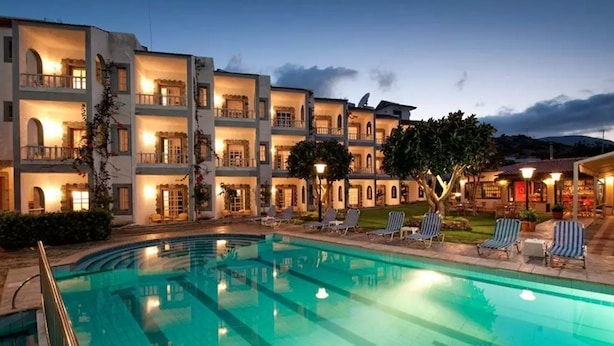 A hotel with a swimming pool, multiple balconies, and outdoor seating areas. - Fan Village (Hersonissos)