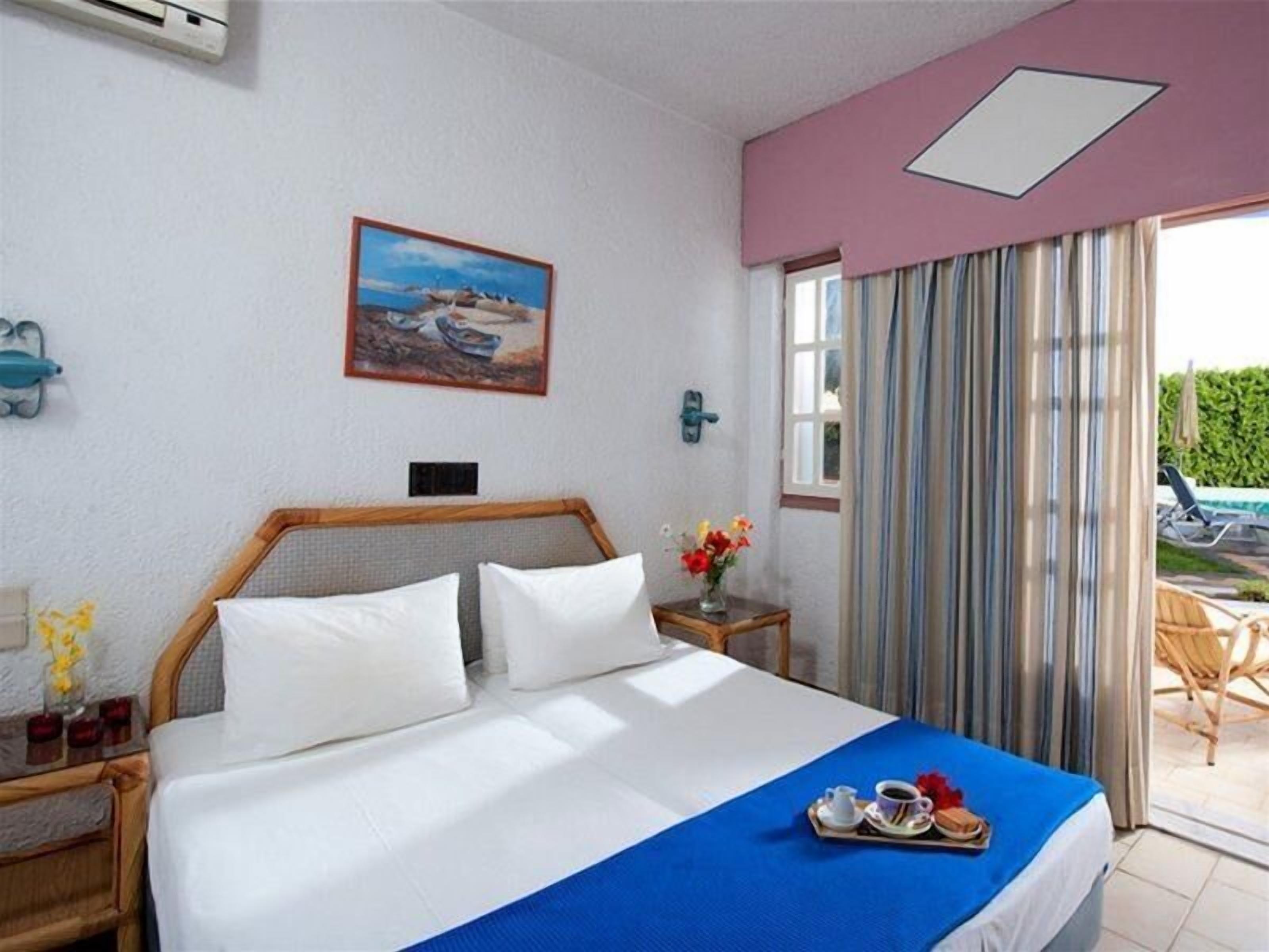 A hotel room with a bed, a painting, a window with curtains, and a view of the outdoors.