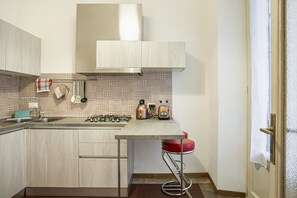 A compact kitchen with a gas stove, a coffee maker, and a toaster.