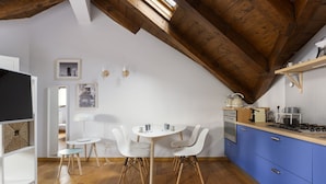 A modern kitchen with blue cabinets, a wooden ceiling, and a dining area with white chairs and a table. - Hostmate - Milano - Farini - Garibaldi (Milano)