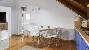 A dining area with a white table and chairs, a kitchen with blue cabinets, and a wooden ceiling. - Hostmate - Milano - Farini - Garibaldi (Milano)