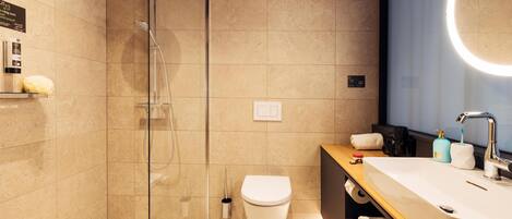 A modern bathroom with a glass-enclosed shower, a white toilet, and a vanity with a sink and mirror.