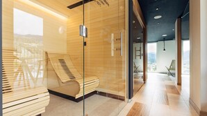 A modern interior with a wooden bench, glass walls, and a view of the outdoors.
