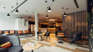 A modern lounge area with seating, tables, and pendant lighting.