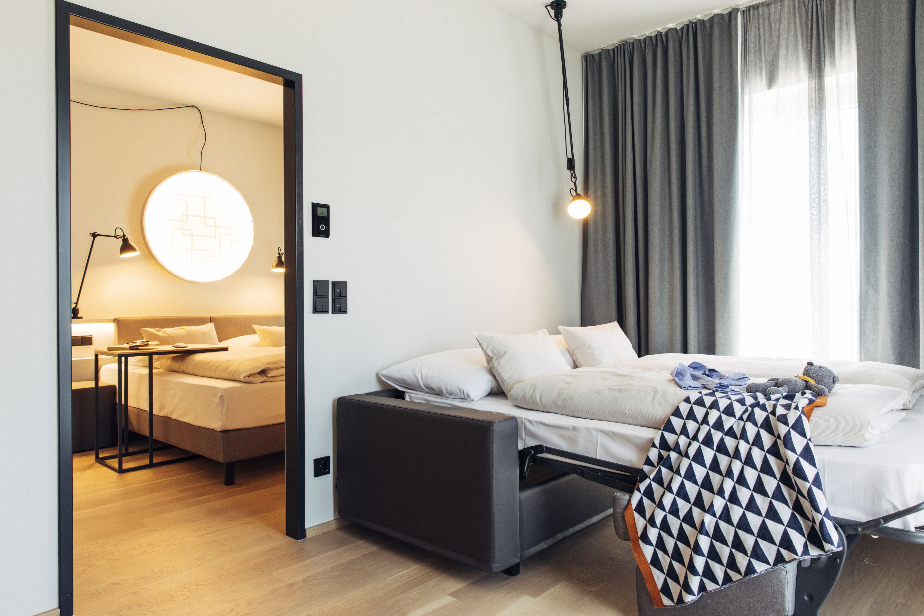 A modern bedroom with a bed, bedside table, and a circular light fixture.