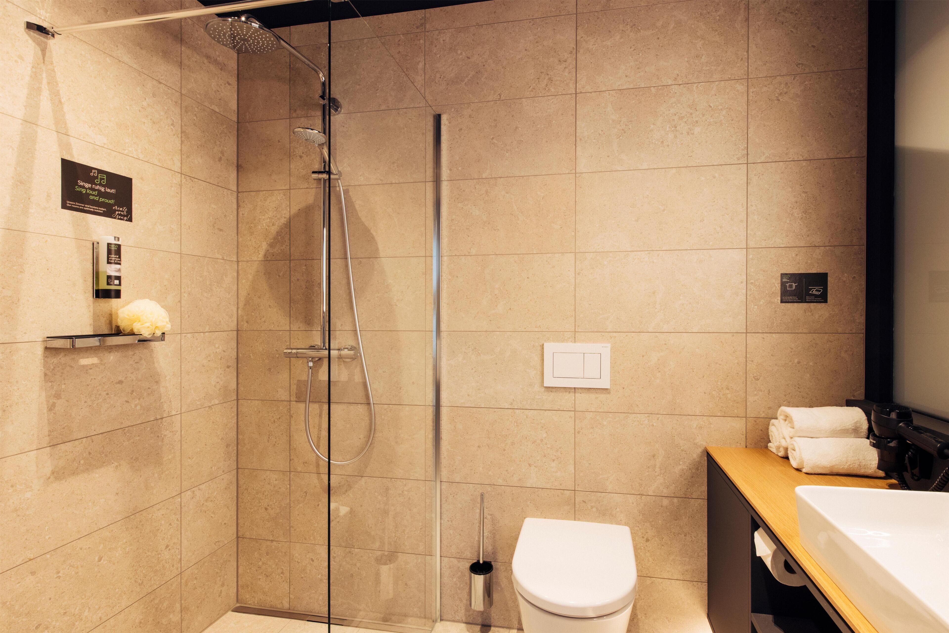 A modern bathroom with a glass-enclosed shower, a white toilet, and a wooden vanity with a mirror.