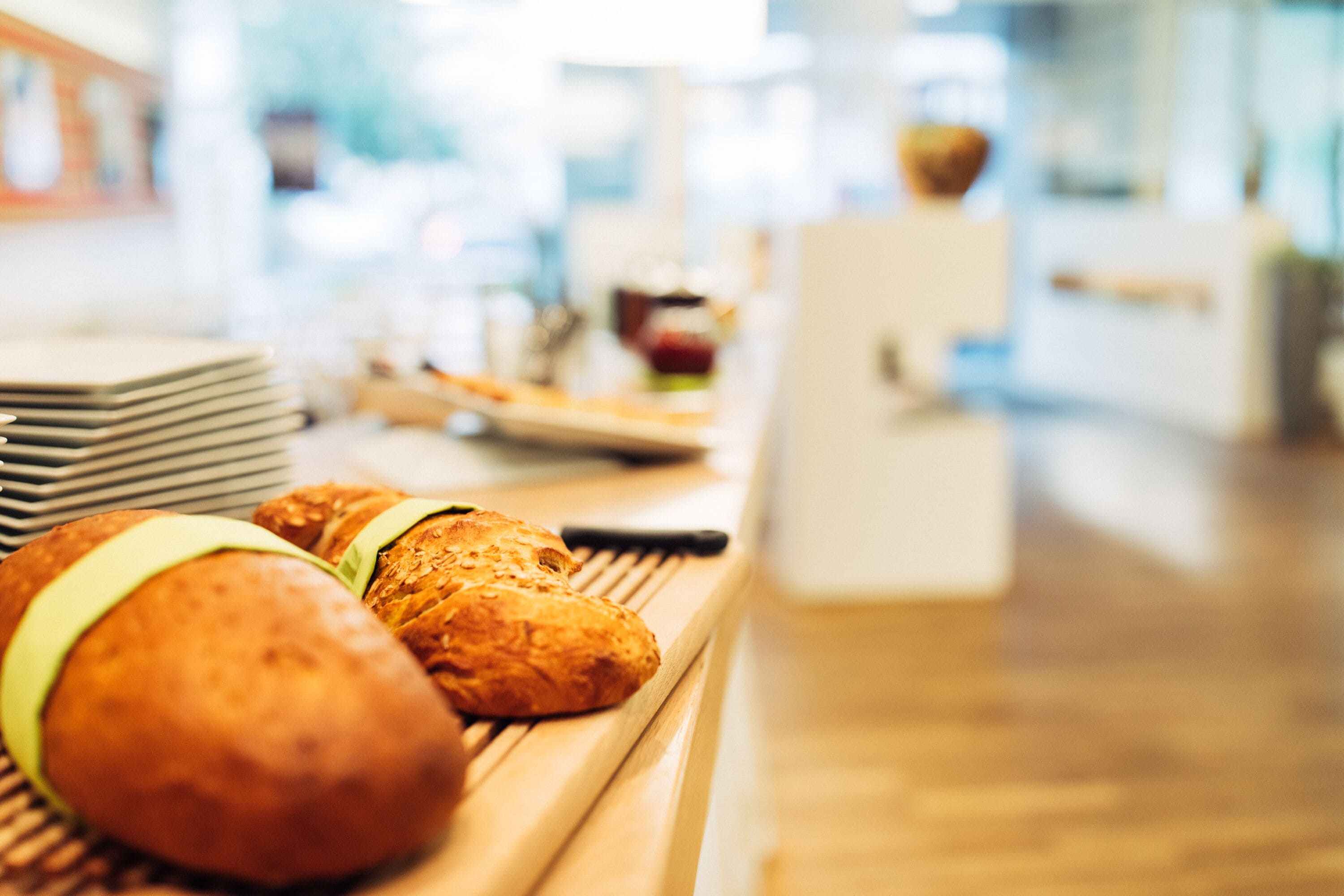 A breakfast buffet with various baked goods and a stack of plates.