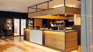 A modern bar area with a wooden counter, bar stools, and a bicycle in the background.