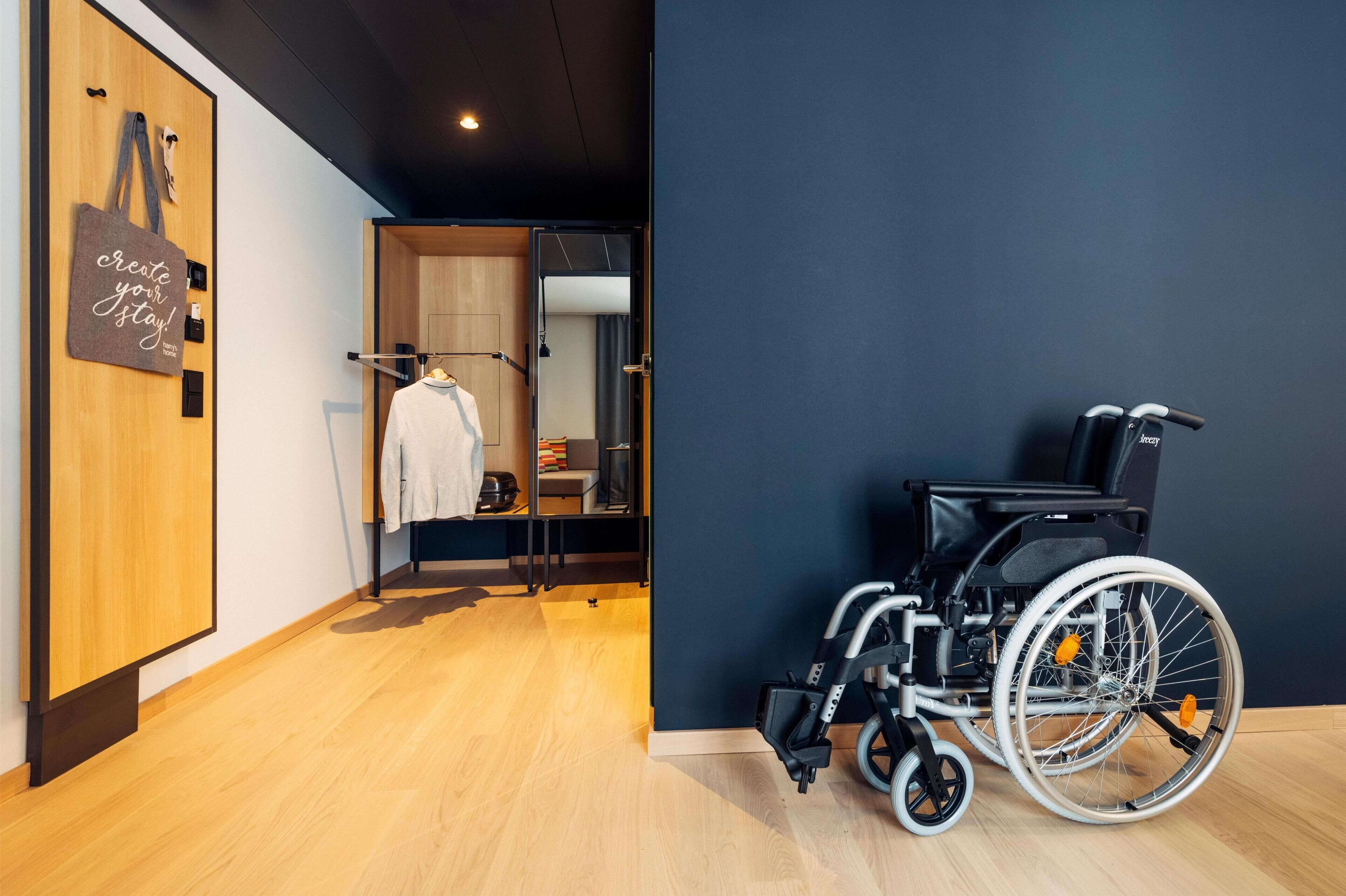 A wheelchair in a room with wooden flooring and a dark blue wall.