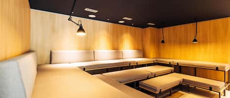 A modern hotel room with a large bed, multiple seating areas, and pendant lighting.