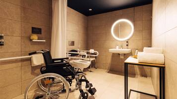 A modern bathroom with a wheelchair, a toilet, a sink, and a mirror with a circular light.