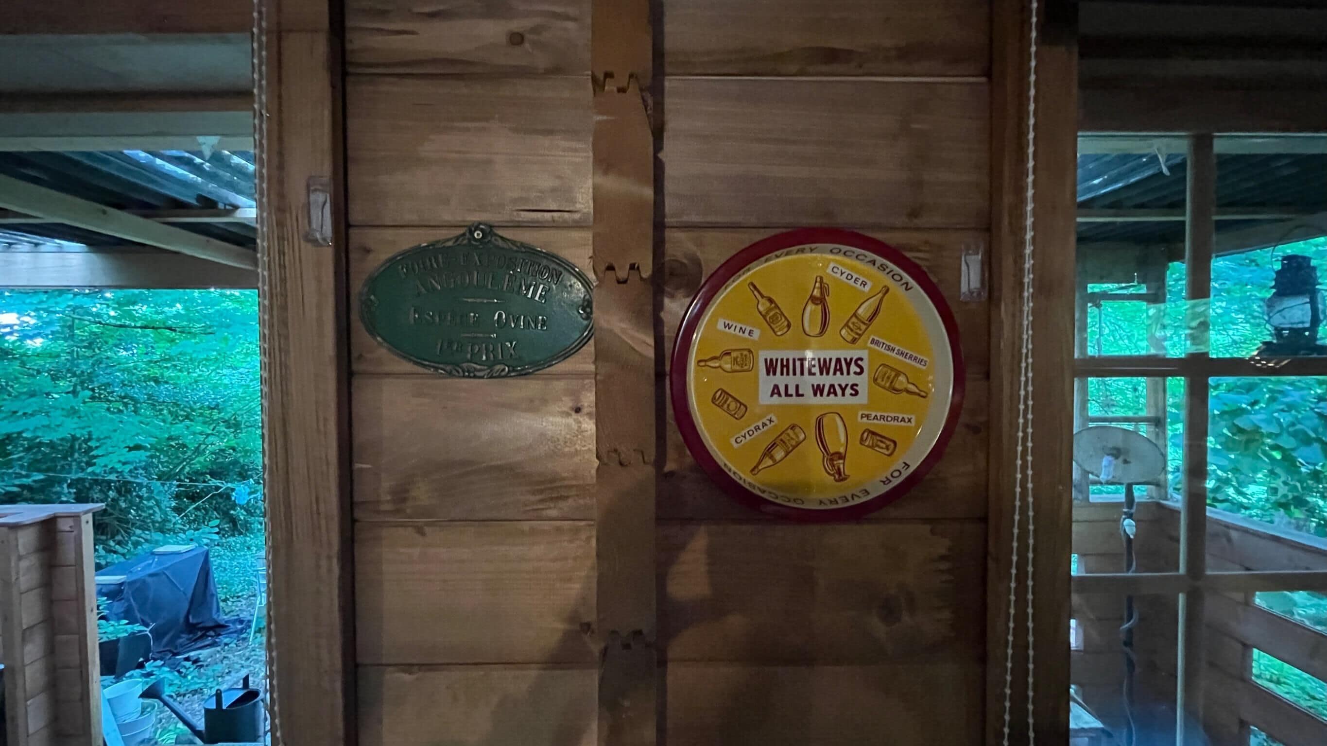A wooden wall with two signs: one indicating a wine cellar and another listing various types of wine available.