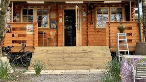 Une cabane en bois avec une véranda, un vélo et une échelle.