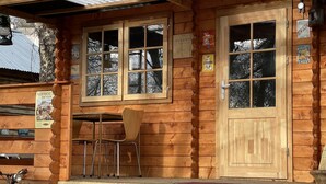 Une cabane en bois avec une véranda, une table et deux chaises.
