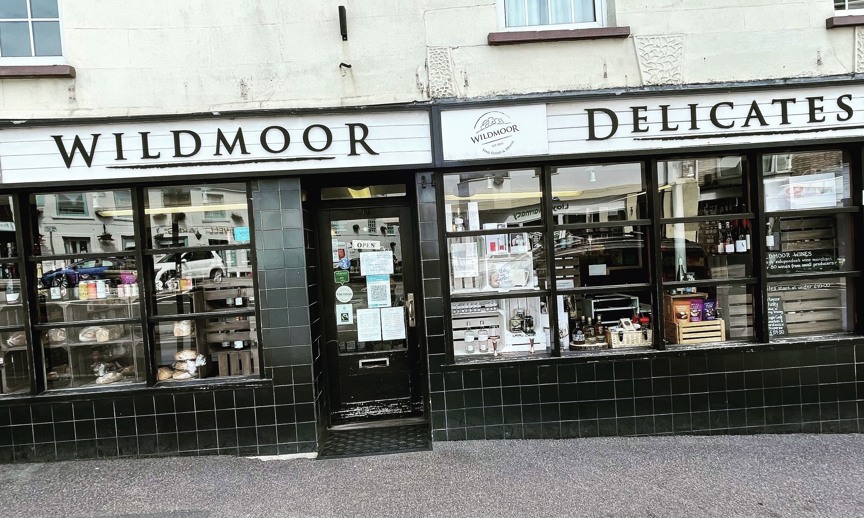 Un escaparate con las señales 'WILDMOOR' y 'DELICATES' que indican un establecimiento de comida y bebida.