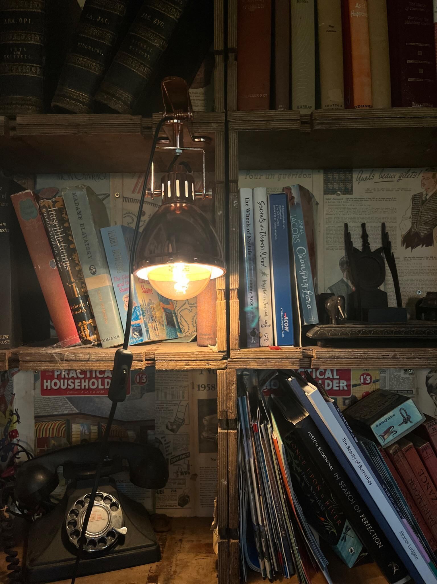 Ein Zimmer mit Schreibtisch, Bücherregalen und einem alten Telefon.