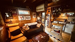 Un salon confortable avec un canapé, un fauteuil et une table basse. Il y a également un coin cuisine équipé d’un réfrigérateur, d’une cuisinière et de divers ustensiles de cuisine.