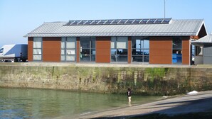 A building with a metal roof, large windows, and a brick facade.