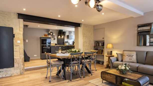 A modern living room with a dining area, wooden flooring, and a sofa.