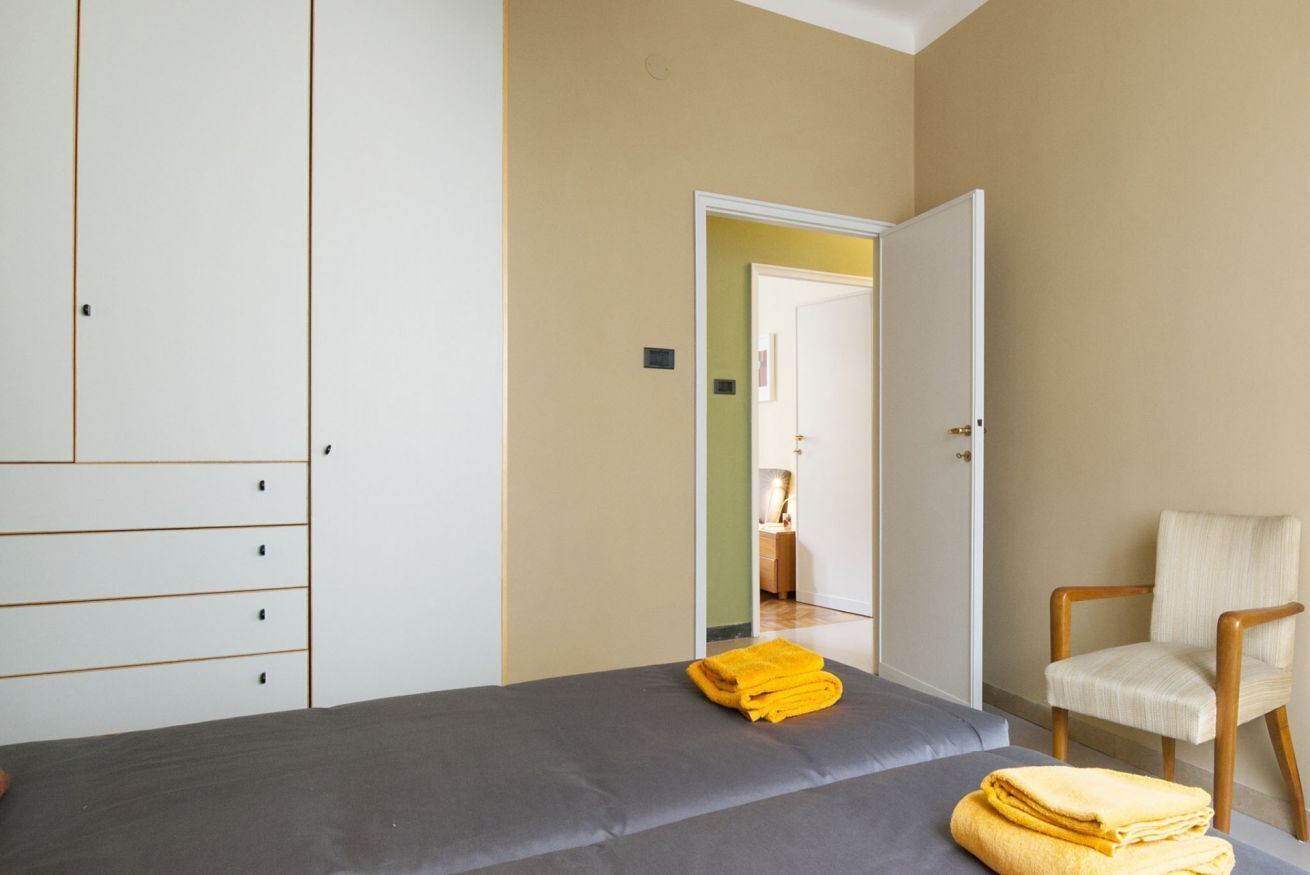 Een slaapkamer met een bed, een stoel en een kledingkast.