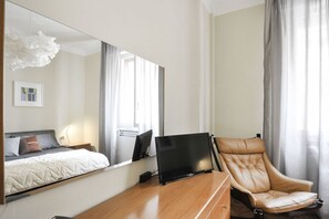 A hotel room with a bed, a desk with a laptop, a leather armchair, and a large mirror. - UR NEST Borgo San Pietro (Bologna)