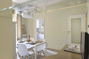 A modern dining area with a white table set for four, a glass ceiling, and a door with a window. - UR NEST Borgo San Pietro (Bologna)