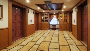 A hallway with wooden doors, a tiled floor, and built-in shelves with various items. - Tokyo Bay Maihama Hotel First Resort (Urayasu)