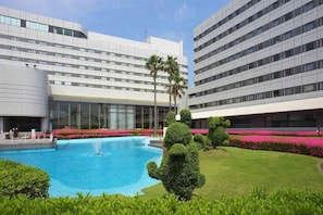 Et hotel med swimmingpool, palmer og velplejede haver.