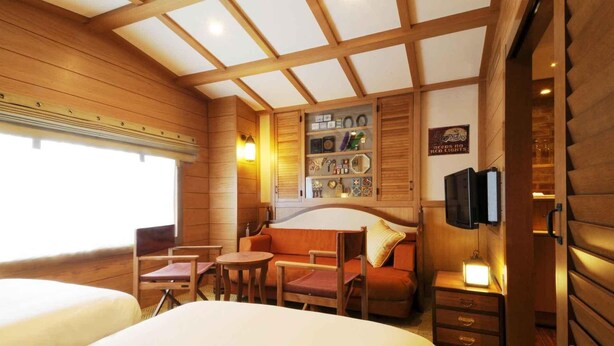 A cozy cabin-style room with a wooden ceiling, a sofa, a small table, and a television mounted on the wall. - Tokyo Bay Maihama Hotel First Resort (Urayasu)