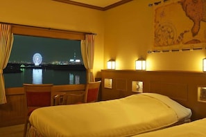 Habitación de hotel con dos camas, vista a una noria nocturna, un mapa en la pared y una ventana con cortinas.