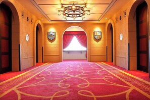 A hotel hallway with a red carpet, arched doorways, and a chandelier. - Tokyo Bay Maihama Hotel First Resort (Urayasu)
