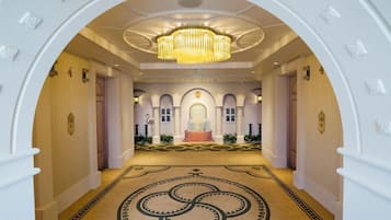 A grand hallway with an arched ceiling, a central chandelier, and a patterned carpet.