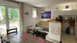 A dining area with a table covered in a floral tablecloth, a sofa, and a kitchen area with cabinets and appliances.