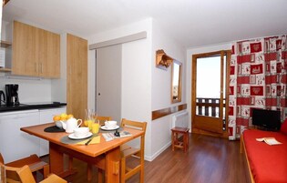 A compact room with a dining area, kitchenette, and a bed.