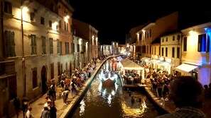 A crowded canal with buildings on either side, illuminated by street lamps. - Pasubio 1 - Three-bedroom apartment with air conditioning near the ocean. (Comacchio)