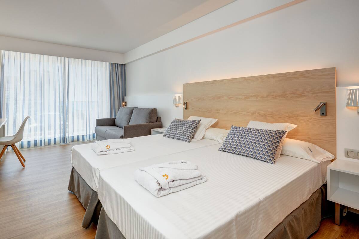 A modern hotel room with a large bed, a desk, and a chair.