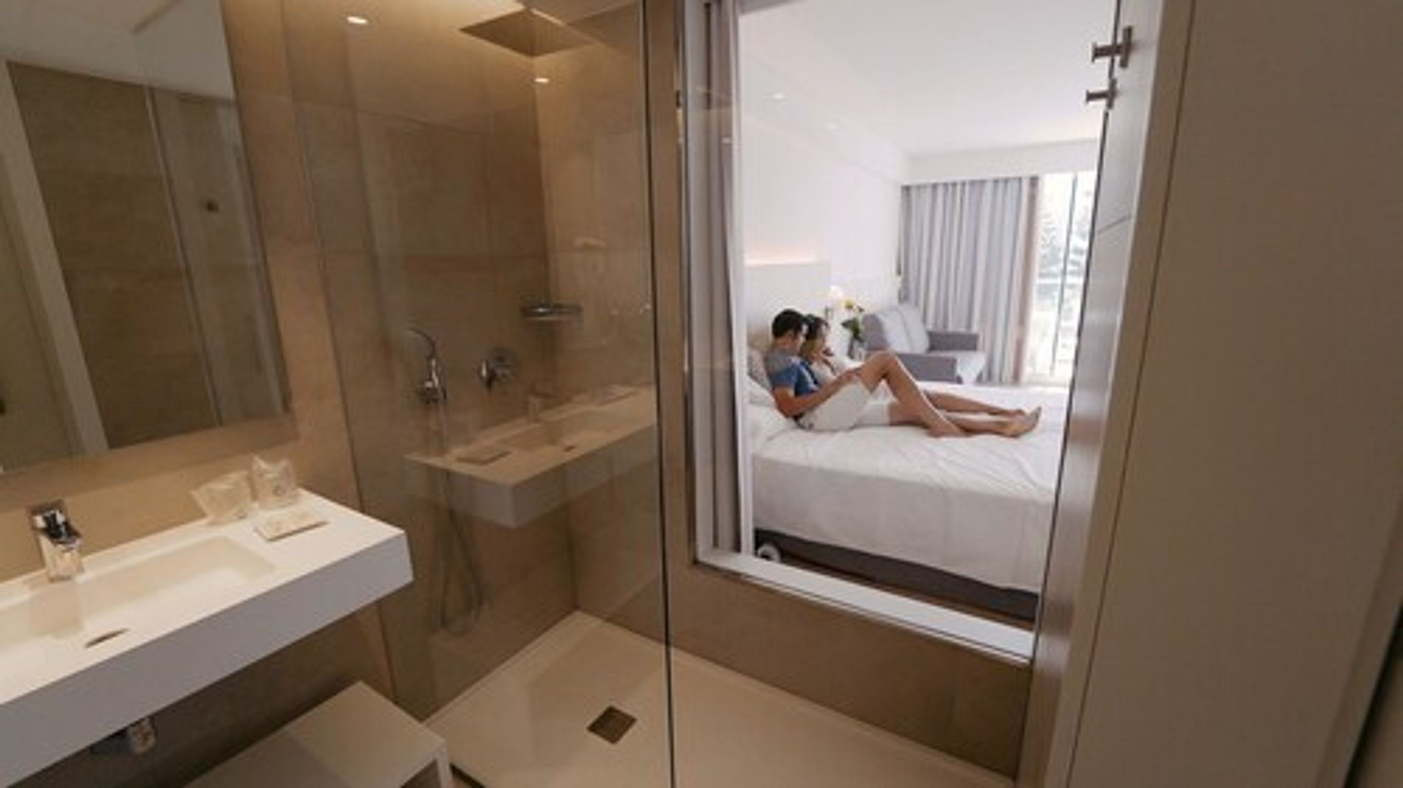 Un baño moderno con cabina de ducha de vidrio, tocador con lavamanos y un espejo grande.