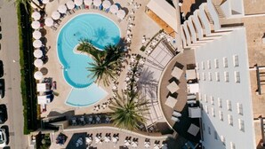 An aerial view of a hotel with a large swimming pool, palm trees, and sun loungers. - Hotel Girasol (Sant Llorenc des Cardassar)