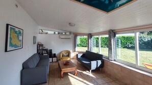 A living room with a sofa, armchair, coffee table, and a map on the wall. - Logement Locatif à Belle-ile : Maison Avec Jardin Partagé (Le Palais)