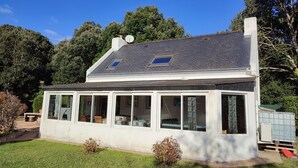 A single-story house with a sloped roof, large windows, and a small attached garage. - Logement Locatif à Belle-ile : Maison Avec Jardin Partagé (Le Palais)