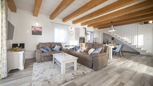 Ein geräumiges Wohnzimmer mit einer Sofagarnitur, einem Couchtisch und einer Treppe, die in eine obere Ebene führt.