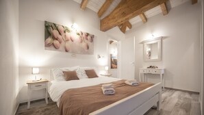 Ein Schlafzimmer mit einem Bett, Nachttischen, einem Spiegel und einem Gemälde an der Wand.