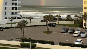 Een meerhoog gebouw met balkons met uitzicht op een parkeerplaats en de oceaan.