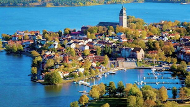 A lakeside town with a prominent church tower, residential buildings, and a marina. - Hotel Bishops Arms Strangnas (Strängnäs)